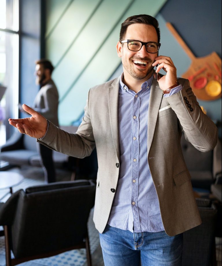 Business, people and office concept. Happy young businessman talking on phone in office