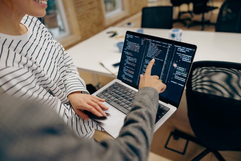 Close up of female computer programmers is coding at laptop while standing in coworking