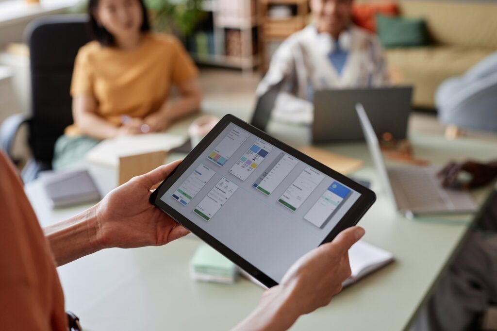 Close up of young businesswoman holding tablet with UX UI designs for mobile app